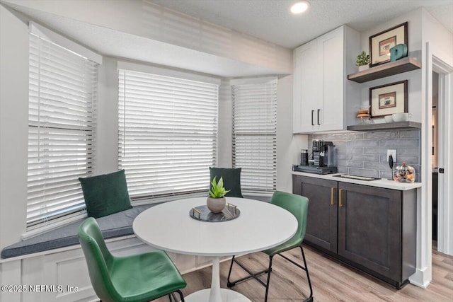 dining space with light hardwood / wood-style floors and a textured ceiling