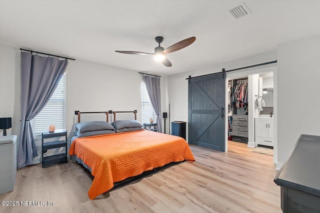 bedroom with a barn door, a spacious closet, light hardwood / wood-style floors, and a closet