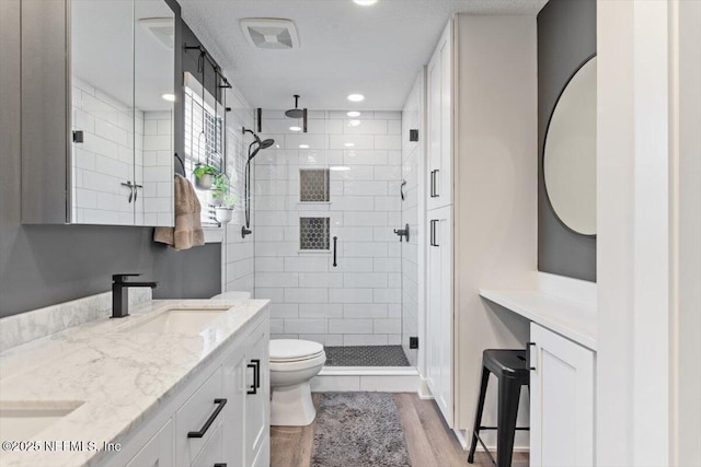 bathroom with vanity, toilet, a shower with shower door, and hardwood / wood-style floors