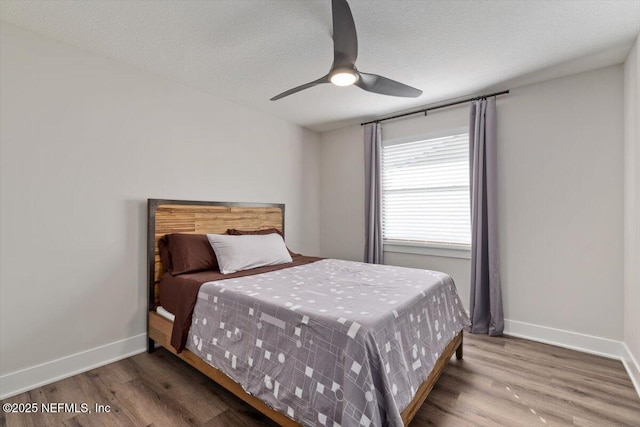 bedroom featuring wood-type flooring, ceiling fan, and a textured ceiling