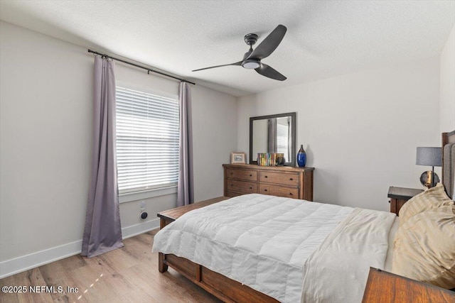 bedroom with ceiling fan, light hardwood / wood-style flooring, and a textured ceiling