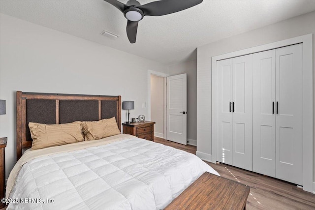 bedroom with ceiling fan, hardwood / wood-style flooring, a closet, and a textured ceiling