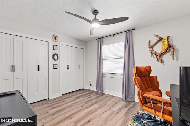 living area with ceiling fan, a textured ceiling, and light hardwood / wood-style flooring