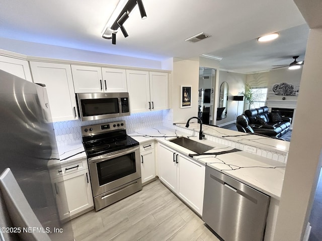 kitchen featuring light stone counters, appliances with stainless steel finishes, sink, and white cabinets