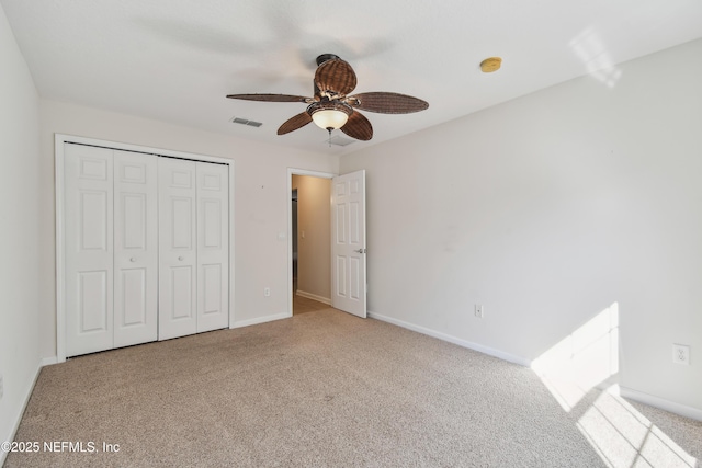 unfurnished bedroom with ceiling fan, a closet, and light carpet