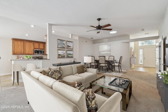 living room featuring ceiling fan, a textured ceiling, and light tile patterned flooring