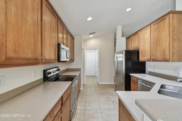 kitchen with light tile patterned flooring, stainless steel appliances, vaulted ceiling, and sink