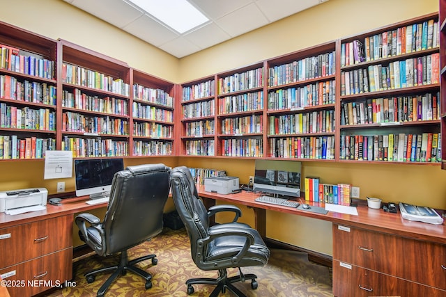 office space with a drop ceiling and built in desk