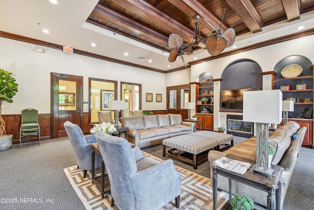 carpeted living room featuring crown molding, wood ceiling, wooden walls, a fireplace, and beamed ceiling