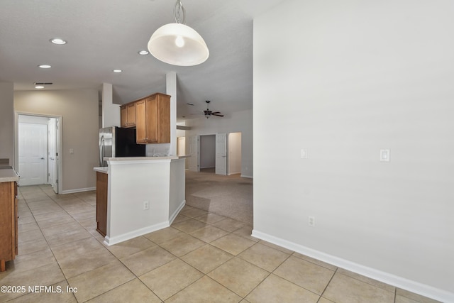 kitchen featuring stainless steel refrigerator, ceiling fan, light tile patterned flooring, vaulted ceiling, and kitchen peninsula