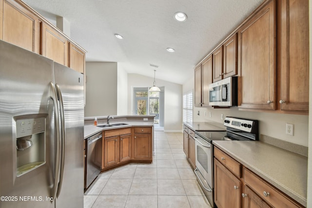 kitchen featuring sink, decorative light fixtures, vaulted ceiling, light tile patterned floors, and stainless steel appliances