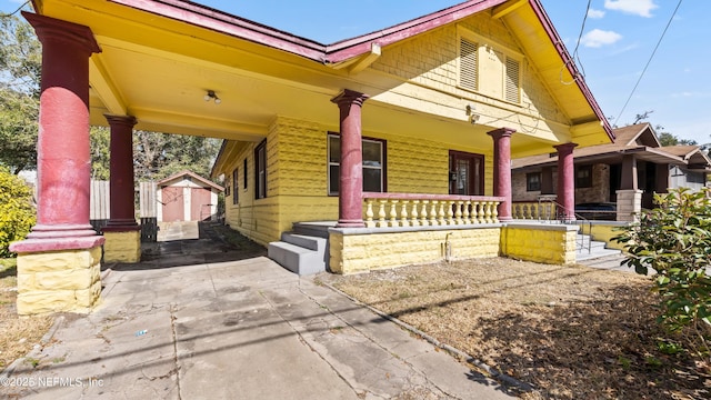 view of front facade with a porch and a storage shed