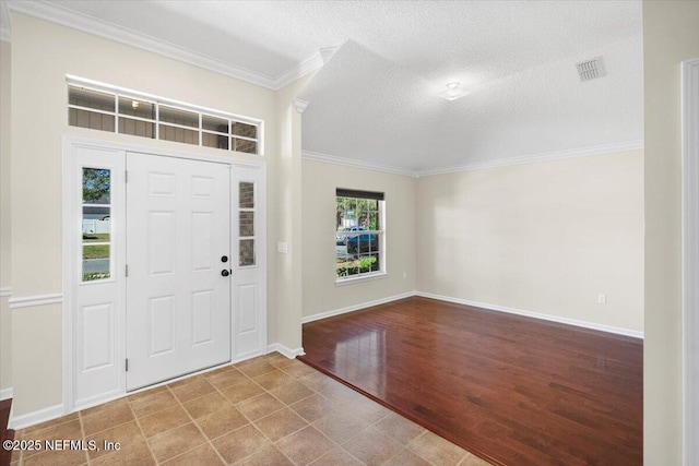 entryway with ornamental molding, wood-type flooring, and a textured ceiling