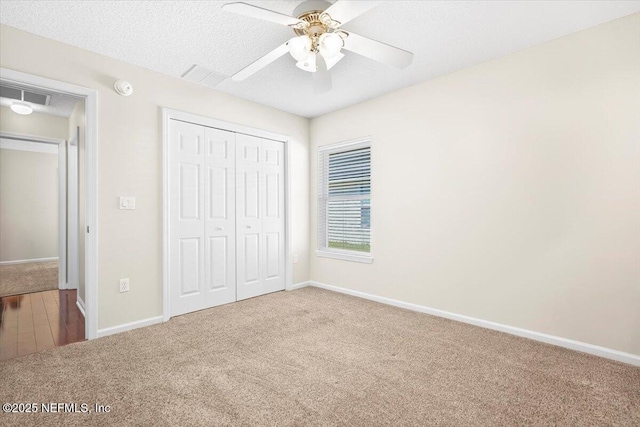 unfurnished bedroom featuring ceiling fan, carpet floors, a textured ceiling, and a closet