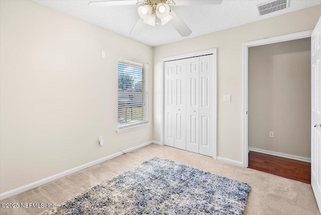 bedroom with a textured ceiling, a closet, ceiling fan, and light colored carpet