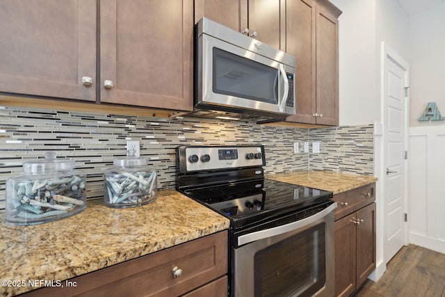 kitchen featuring backsplash, appliances with stainless steel finishes, dark wood-type flooring, and light stone counters