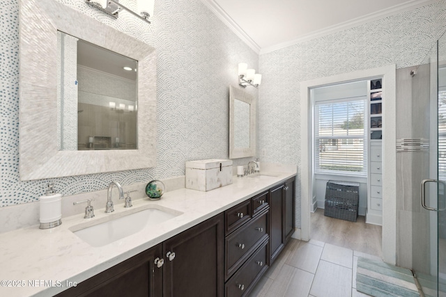 bathroom with crown molding, a sink, and wallpapered walls