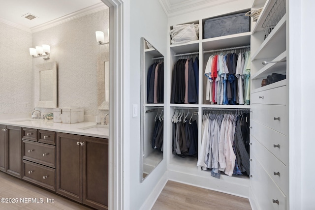 interior space featuring double vanity, wallpapered walls, crown molding, and a sink