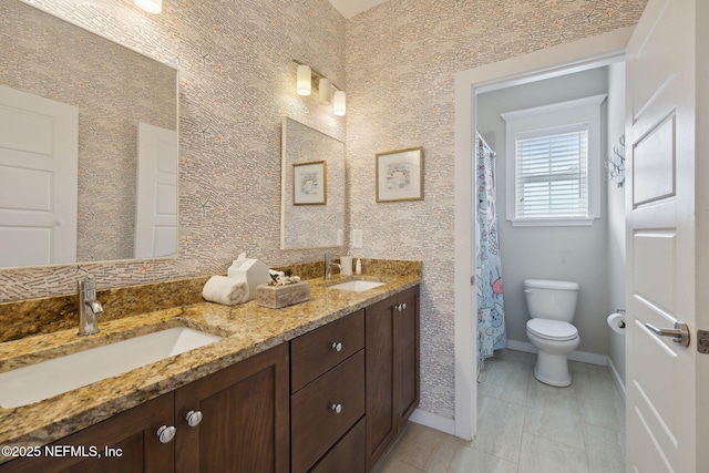 bathroom with baseboards, a sink, toilet, and double vanity