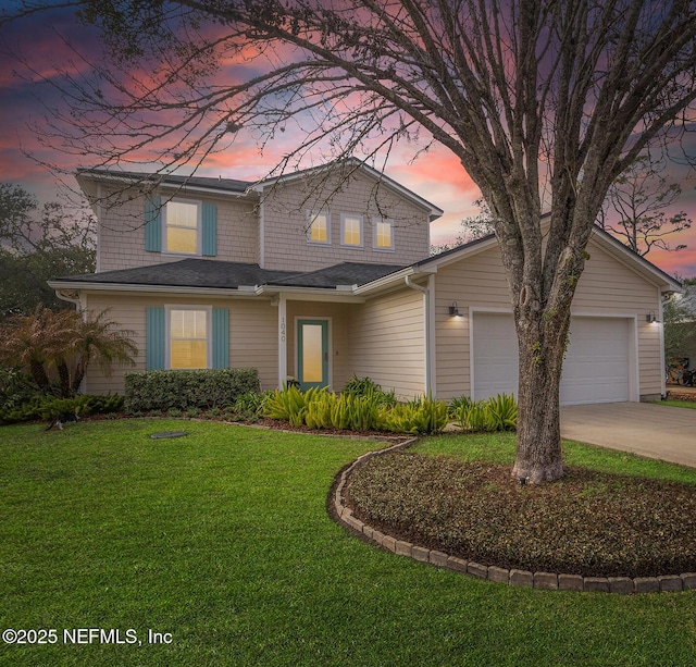 traditional-style house with a garage, a yard, and concrete driveway