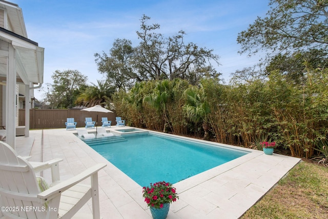 view of swimming pool featuring a pool with connected hot tub, fence, and a patio