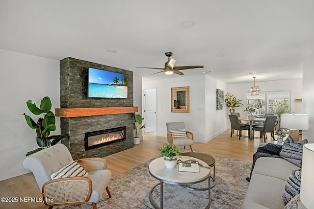 living room featuring a fireplace, ceiling fan, and light wood-type flooring