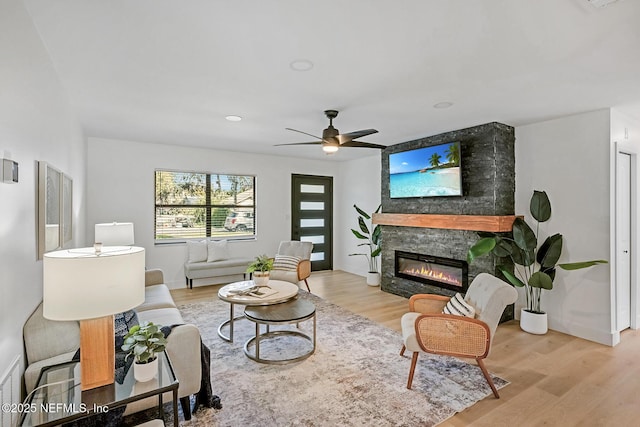 living room featuring a fireplace, light wood-type flooring, and ceiling fan