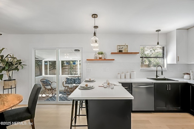 kitchen featuring sink, light hardwood / wood-style flooring, dishwasher, and decorative light fixtures