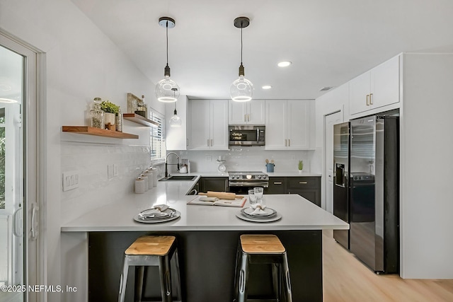 kitchen with white cabinets, stainless steel appliances, a kitchen breakfast bar, and kitchen peninsula