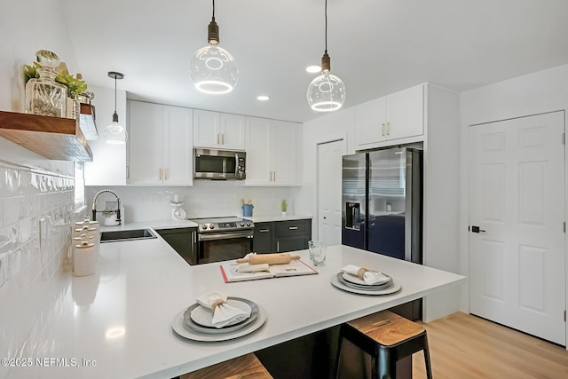 kitchen with white cabinets, a kitchen bar, stainless steel appliances, and sink