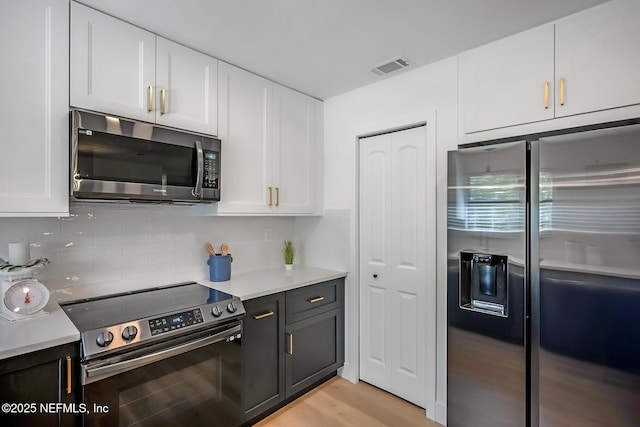 kitchen with decorative backsplash, stainless steel appliances, white cabinetry, and light hardwood / wood-style flooring