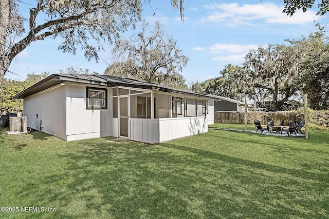 back of house with a yard, a sunroom, central air condition unit, and a fire pit