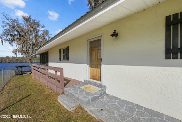 entrance to property featuring a water view and a lawn