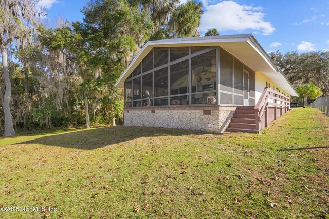 view of side of home with a sunroom and a lawn