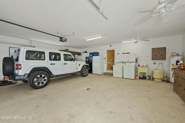 garage featuring sink, a garage door opener, water heater, white refrigerator, and washing machine and clothes dryer