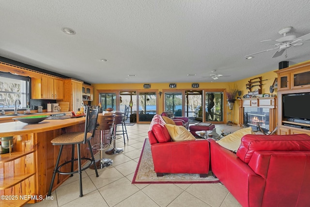 tiled living room with sink, a textured ceiling, and ceiling fan