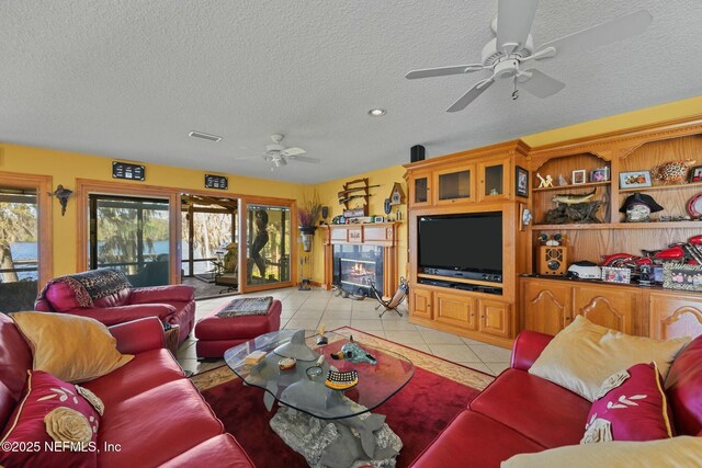 tiled living room with ceiling fan and a textured ceiling