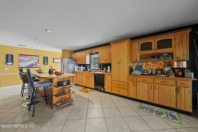 kitchen featuring stainless steel fridge with ice dispenser, light tile patterned floors, sink, and black dishwasher