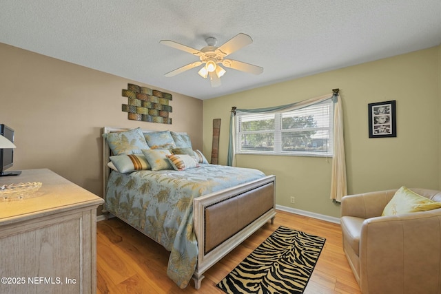 bedroom with ceiling fan, a textured ceiling, and light wood-type flooring