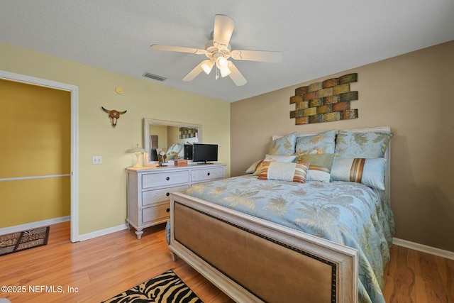 bedroom with ceiling fan, light hardwood / wood-style flooring, and a textured ceiling