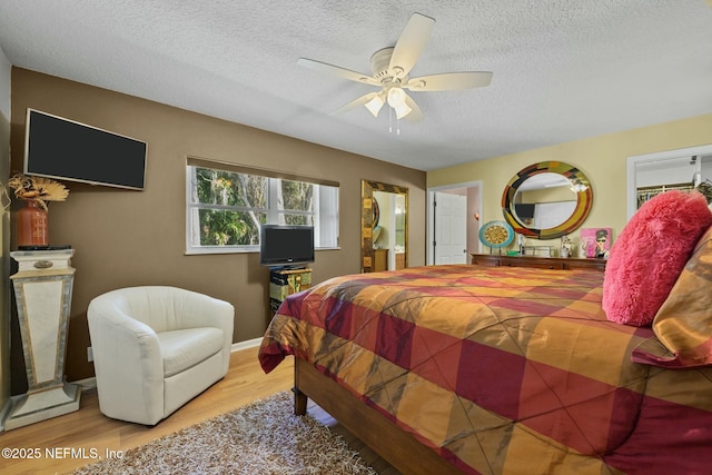 bedroom with ceiling fan, a textured ceiling, and light wood-type flooring