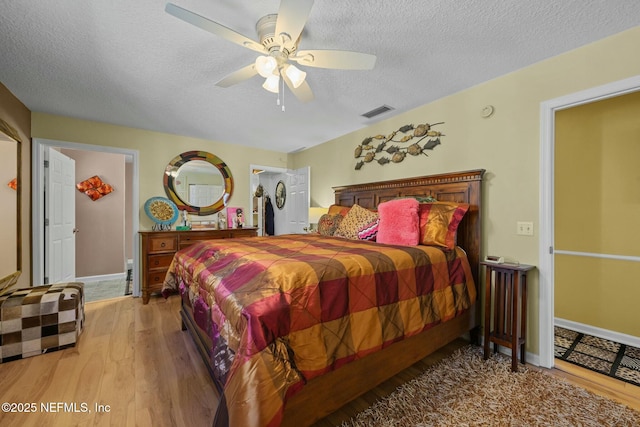 bedroom with ceiling fan, wood-type flooring, and a textured ceiling