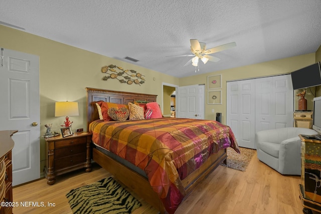 bedroom featuring ceiling fan, a closet, light hardwood / wood-style floors, and a textured ceiling