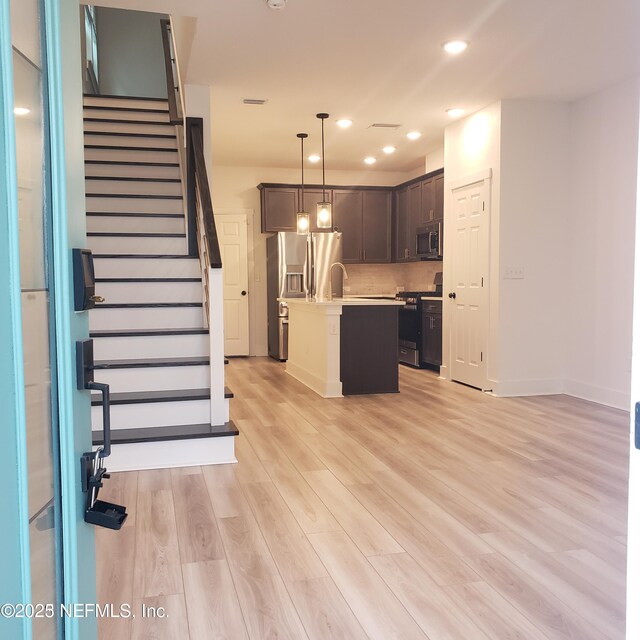 11107 Quasar Ct, Jacksonville, FL 32256 - kitchen with dark brown cabinets, light wood-style floors, light countertops, baseboards, and appliances with stainless steel finishes