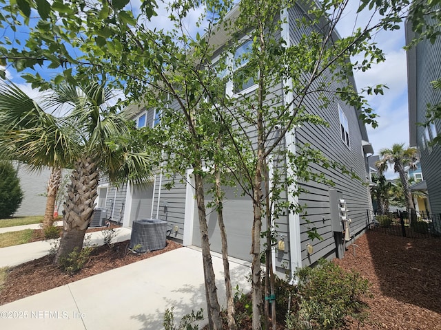 11107 Quasar Ct, Jacksonville, FL 32256 - view of side of property featuring a garage, concrete driveway, fence, and central AC unit