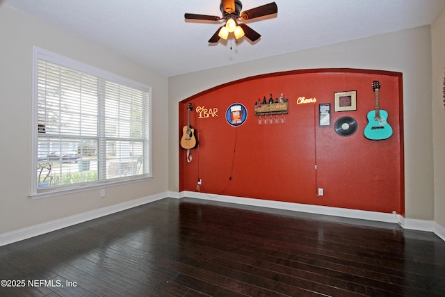 unfurnished room featuring dark wood-type flooring and ceiling fan