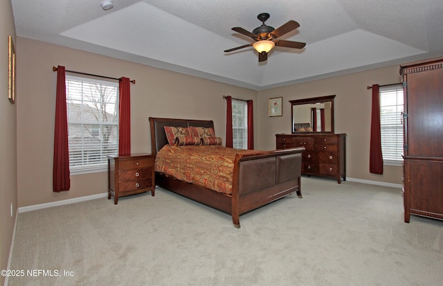 carpeted bedroom featuring a raised ceiling, ceiling fan, and a textured ceiling