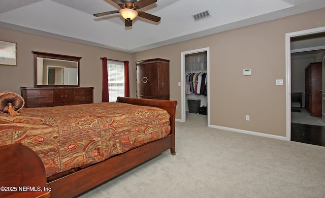 bedroom with a spacious closet, light carpet, ceiling fan, and a closet