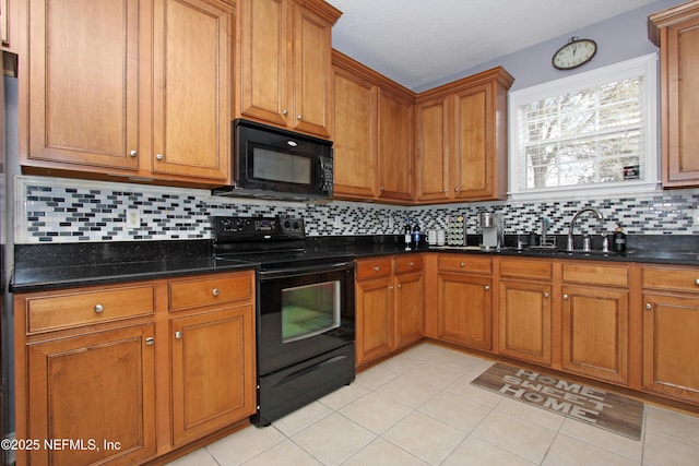 kitchen with sink, light tile patterned floors, dark stone countertops, decorative backsplash, and black appliances