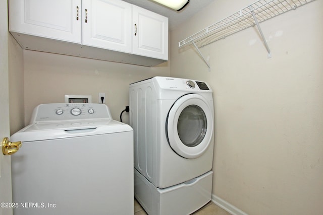 clothes washing area featuring cabinets and washing machine and clothes dryer